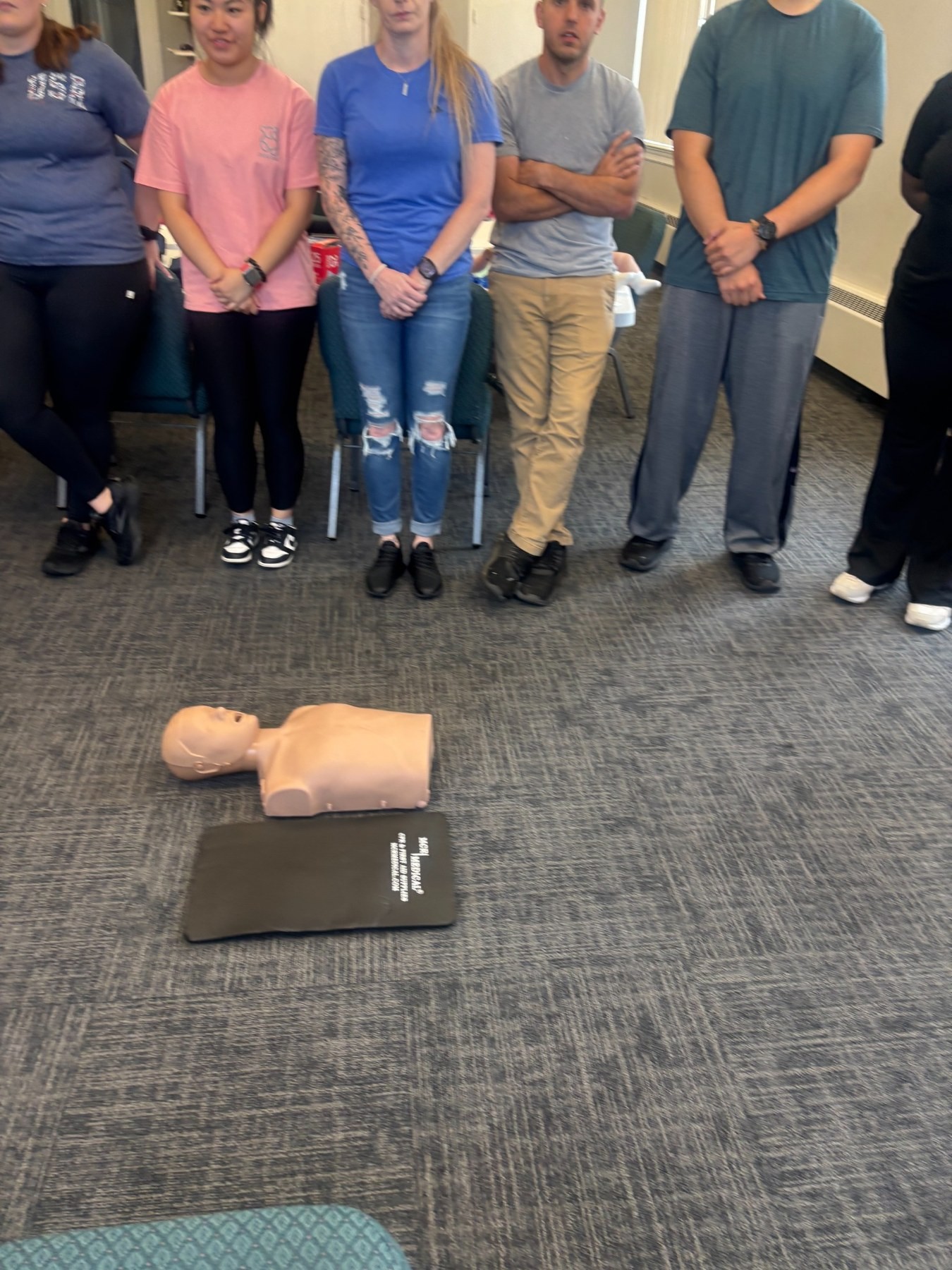 Adult participants observing a CPR training manikin during a group class